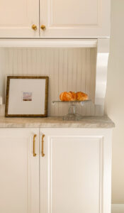 Traditional white buffet cabinetry with corbels and bead board backsplash