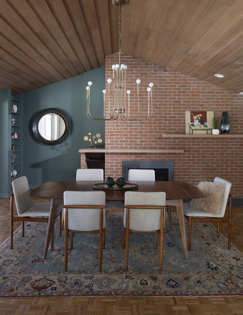 mid-century modern dining room, mid-century chandelier, mixed textures, wood ceiling, red brick wall, open shelving, accent color wall